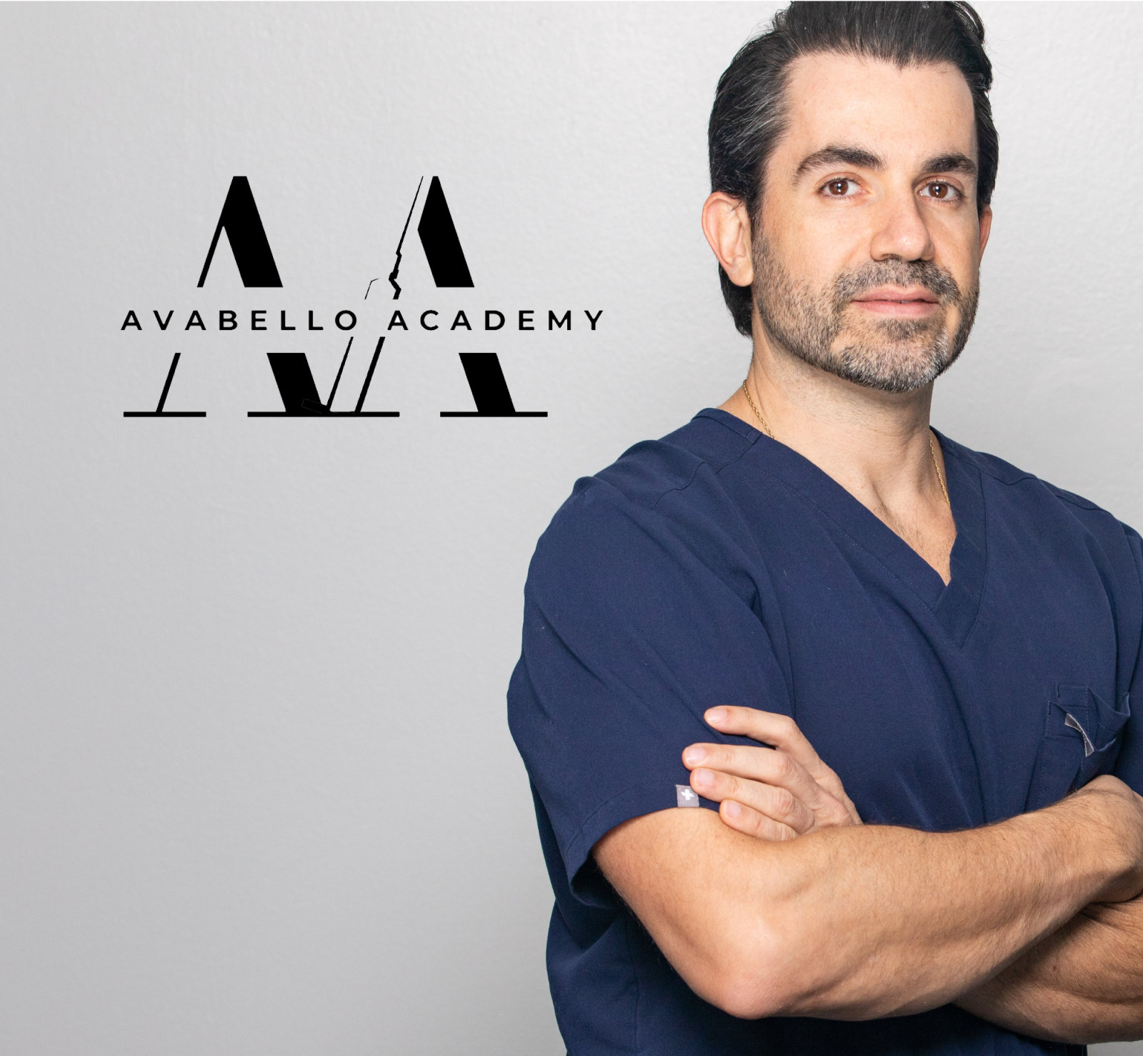 A man in navy scrubs stands with arms crossed next to an Avabello Academy logo on a light gray background.