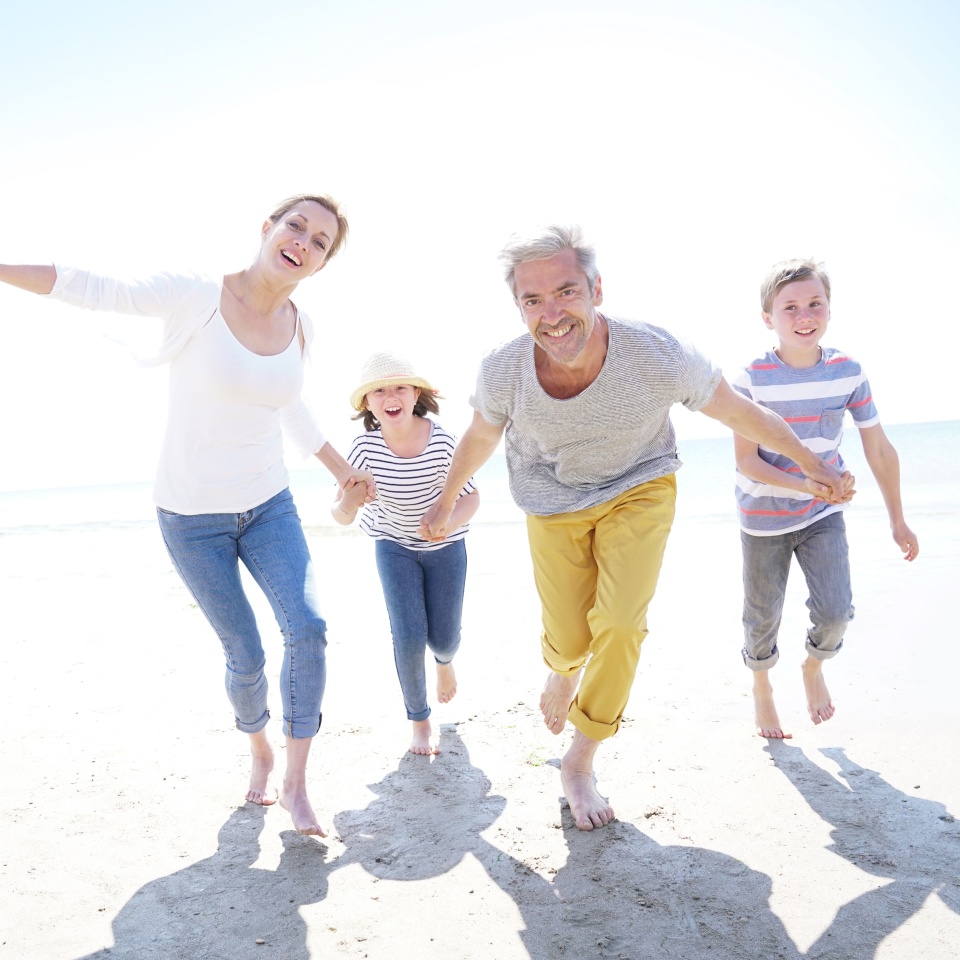 Happy family of four walking on sandy beach