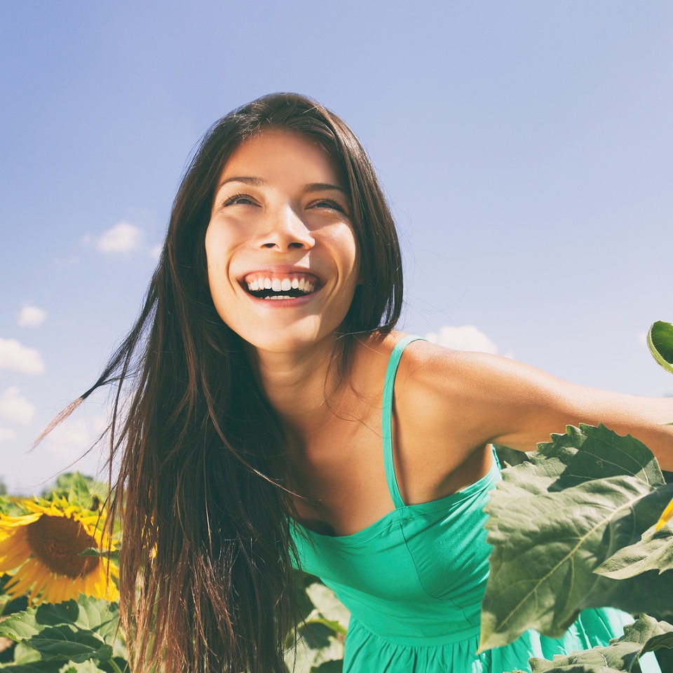Spring flower field nature woman happy allergy-free breathing clean air in summer sunshine. Pollen allergies concept. Asian smiling girl portrait. Outdoors lifestyle happiness.