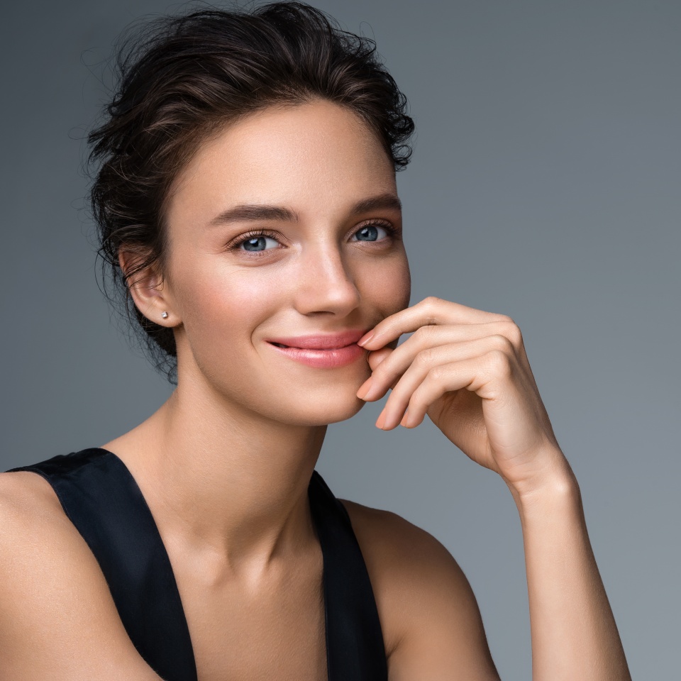 Beautiful woman with perfect makeup on gray background. Beauty and skin care concept