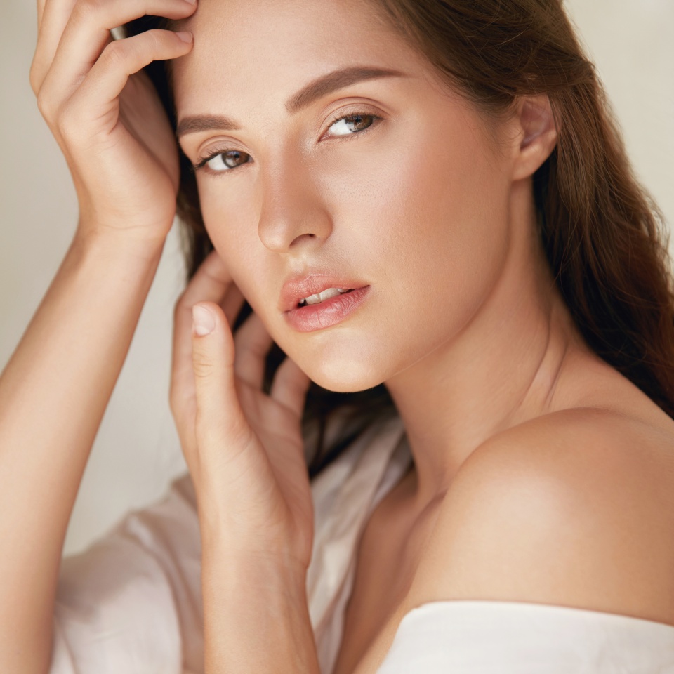 Woman. Beauty Portrait Of Young Model Touching Face. Beautiful Brunette With Natural Makeup And Perfect Skin Looking Aside.