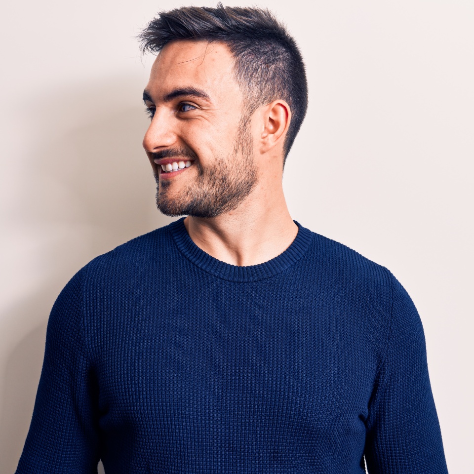Young handsome man with beard wearing casual sweater standing over white background looking to side, relax profile pose with natural face and confident smile.
