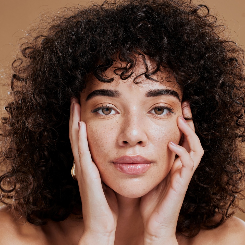 Woman, hands on face and afro hair care for beauty wellness in studio. Skincare dermatology wellness, African girl model portrait and cosmetics makeup headshot for healthy natural skin or facial care