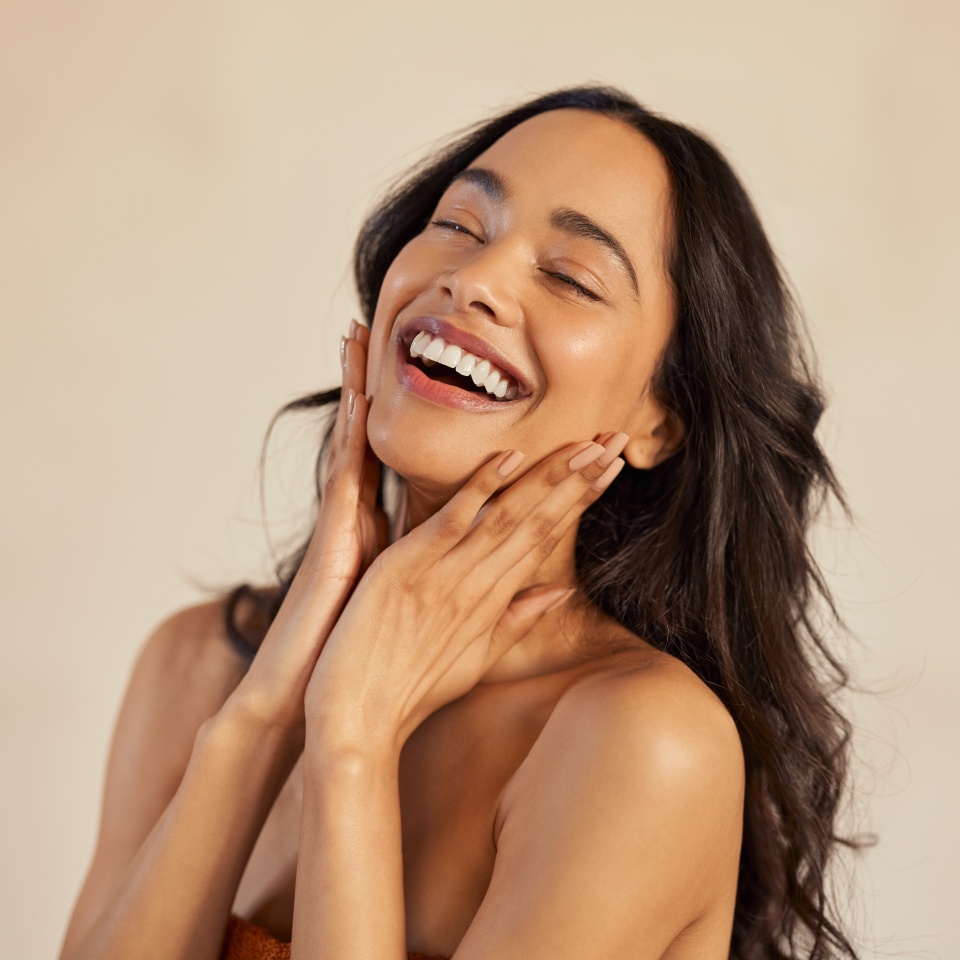 Multiethnic young woman touching her clean and healthy face against background with closed eyes. Latin hispanic woman feeling good. Natural beauty portrait of mexican girl with black long hair.