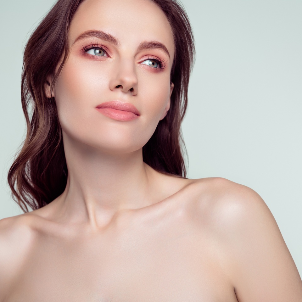 Retrato fotográfico de una chica joven y bonita, modelo encantadora comprando en un salón de spa aislado sobre un fondo de color gris claro