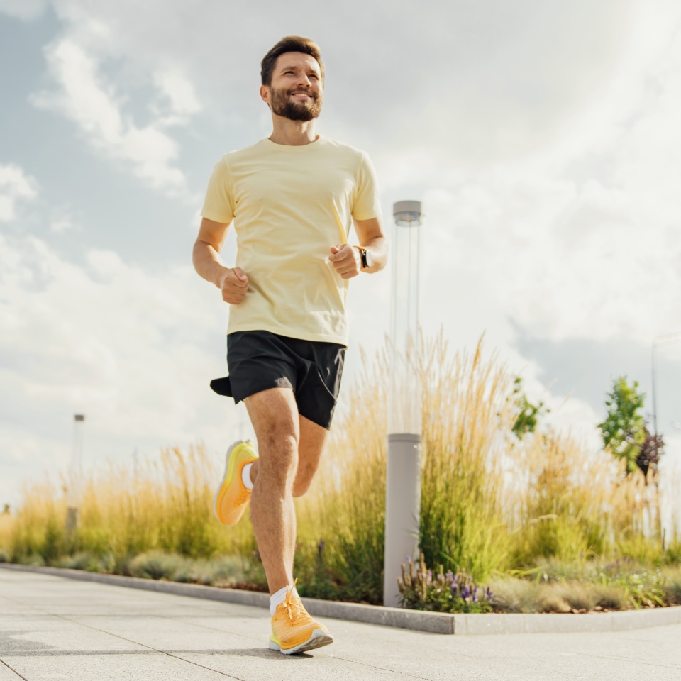 Hombre corriendo en un parque urbano en un día soleado, concepto de fitness y estilo de vida saludable.
