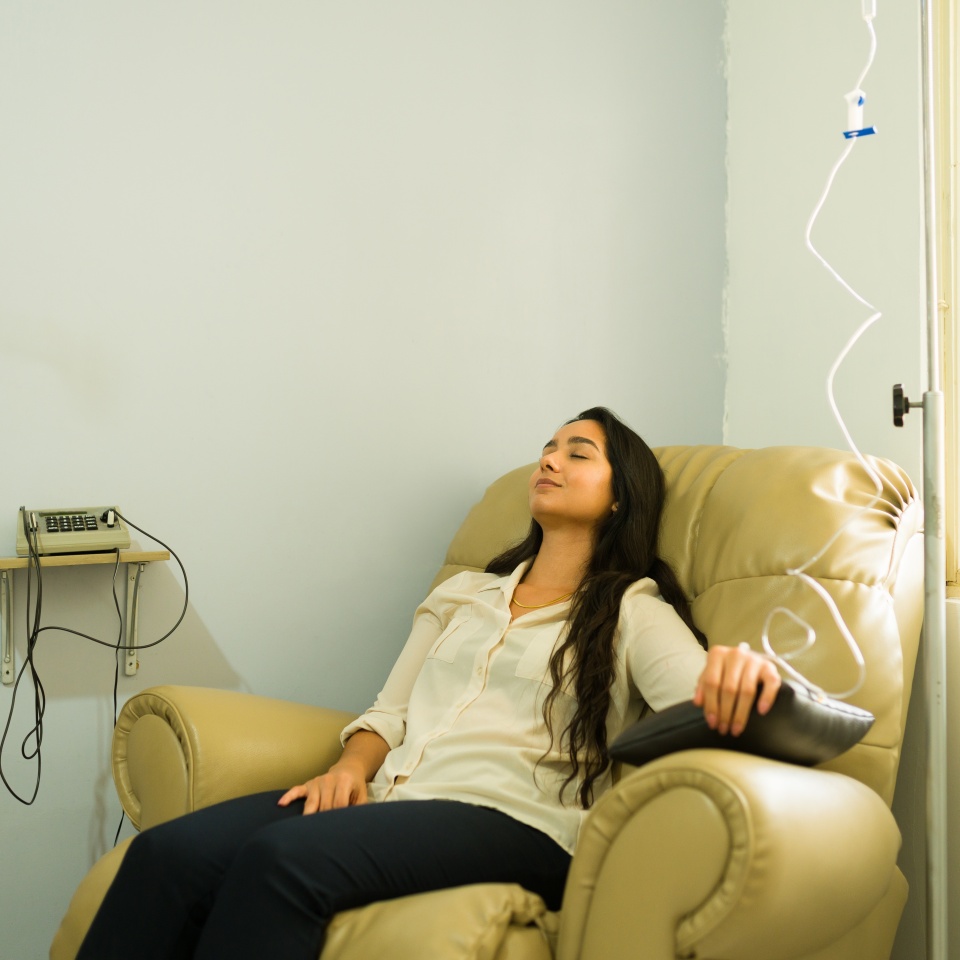 Happy attractive woman relaxing while getting IV drip and vitamin minerals therapy for a better health with a myers cocktail