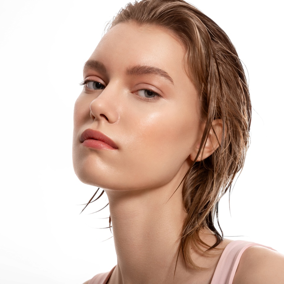 Young woman with soft pure skin, nude makeup and wet blond hair