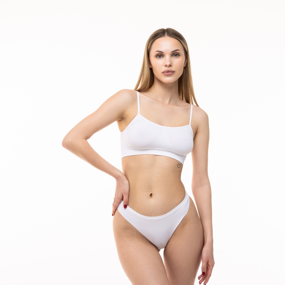 Young nice lady woman with slim body perfect skin wears nude top bra lingerie stand hold hands crossed folded look camera isolated on plain pastel light beige background. Lifestyle diet fit concept