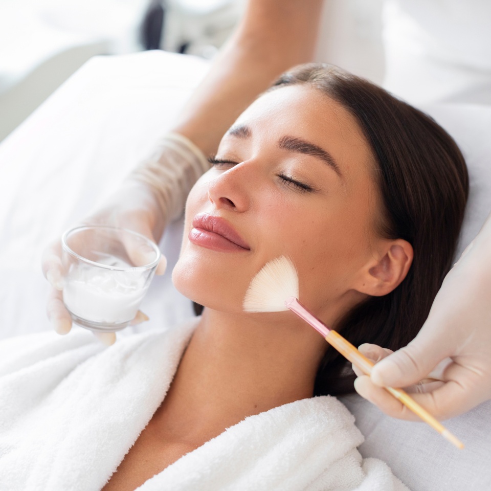 Cosmetologist cleaning face of a beautiful European woman with special gel before applying mask, peeling or scrub. Facial skin care procedures in beauty salon