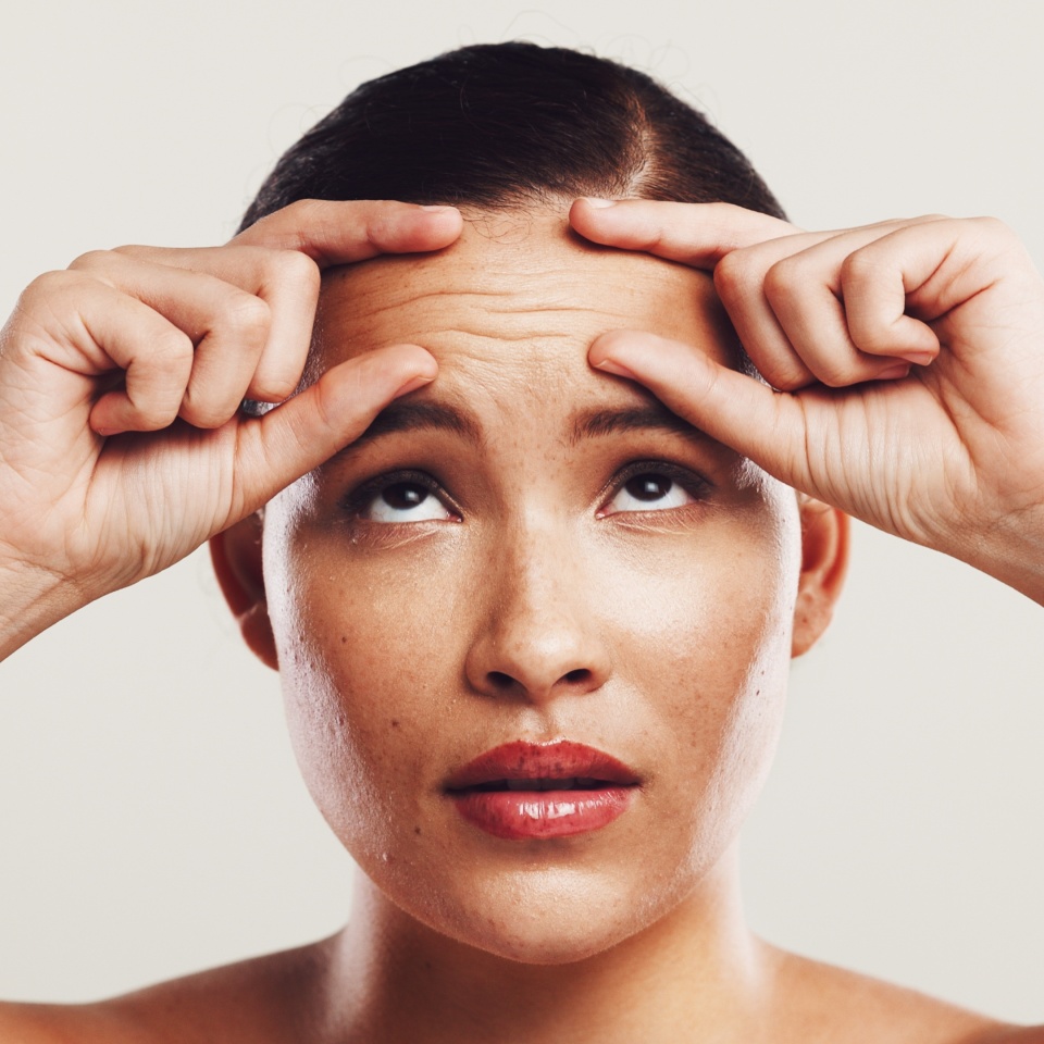 Wrinkles, forehead and woman with skincare, beauty and plastic surgery on white studio background. Person, worry and model with cosmetic facial filler, wellness and health with dermatology and stress