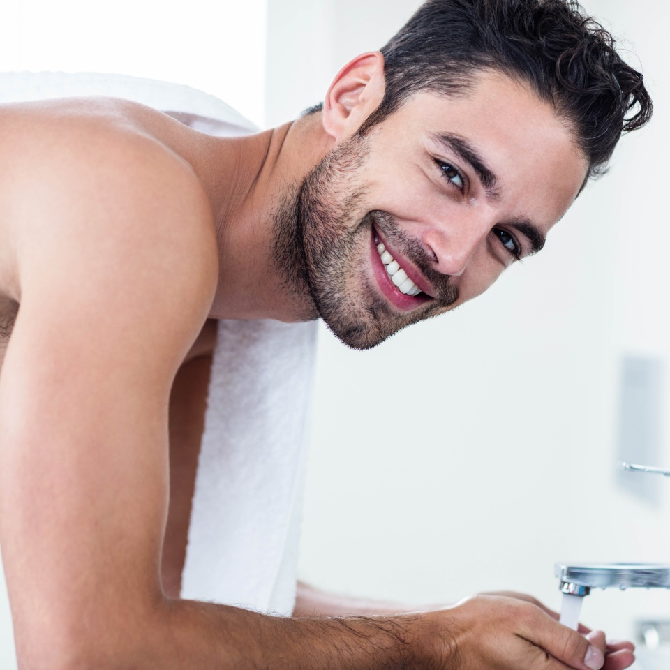 Man washing his face in sink in bathroom