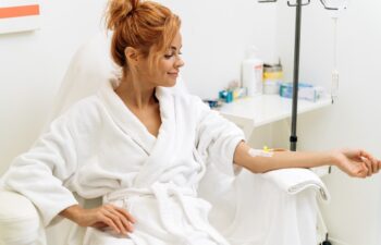 Portrait of mindful woman sitting in armchair and closed eyes while receiving IV infusion with vitamins. Cosmetology and medicine concept